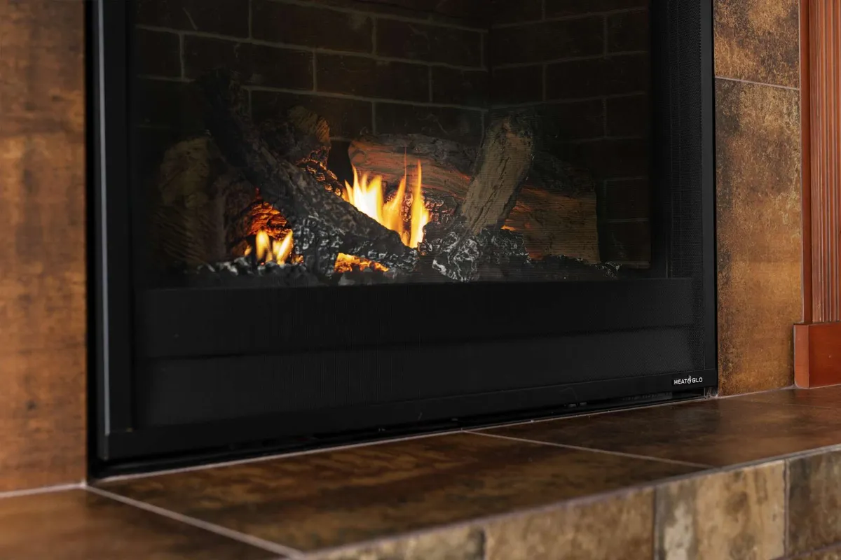 A warm, inviting living room scene centered on a glowing fireplace with stacked logs, creating a cozy ambiance ideal for unwinding with a glass of wine or enjoying intimate group gatherings.