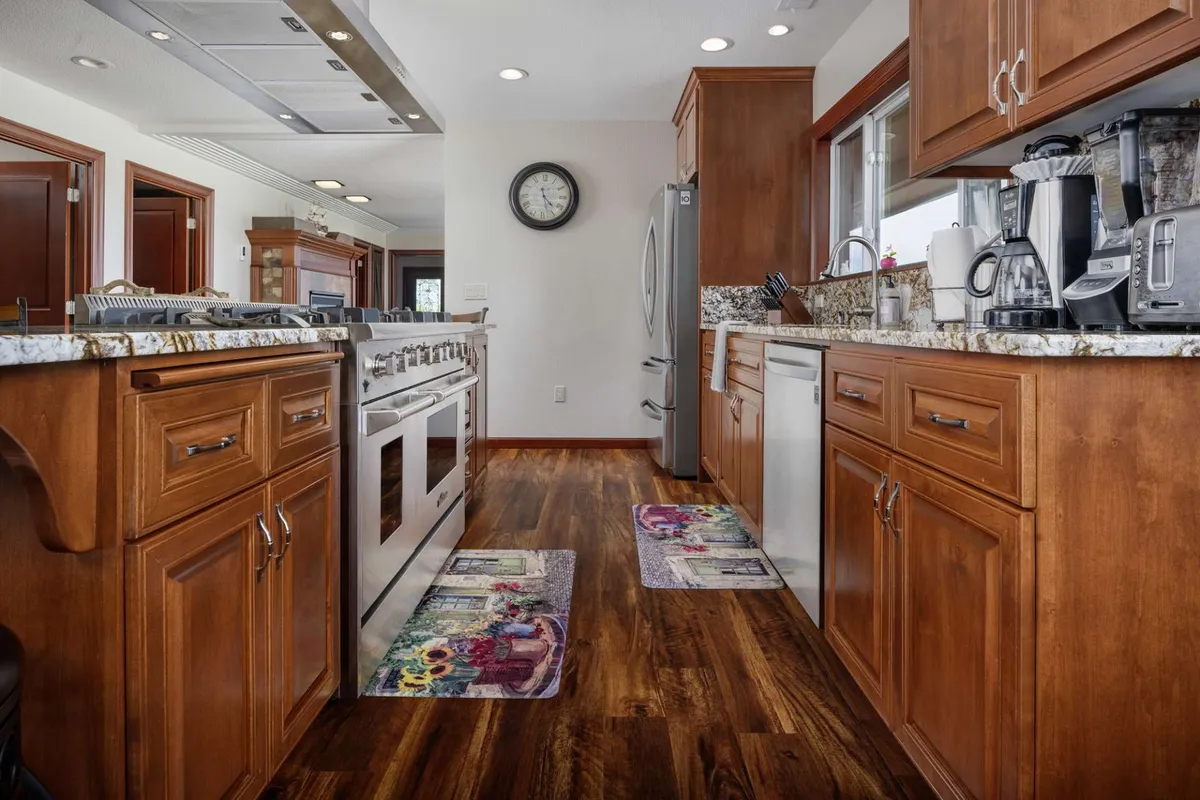 An inviting kitchen featuring granite countertops, sleek stainless steel appliances, and a spacious kitchen island. Warm wooden cabinetry and ample prep space set the stage for both holiday feasts and everyday meals.