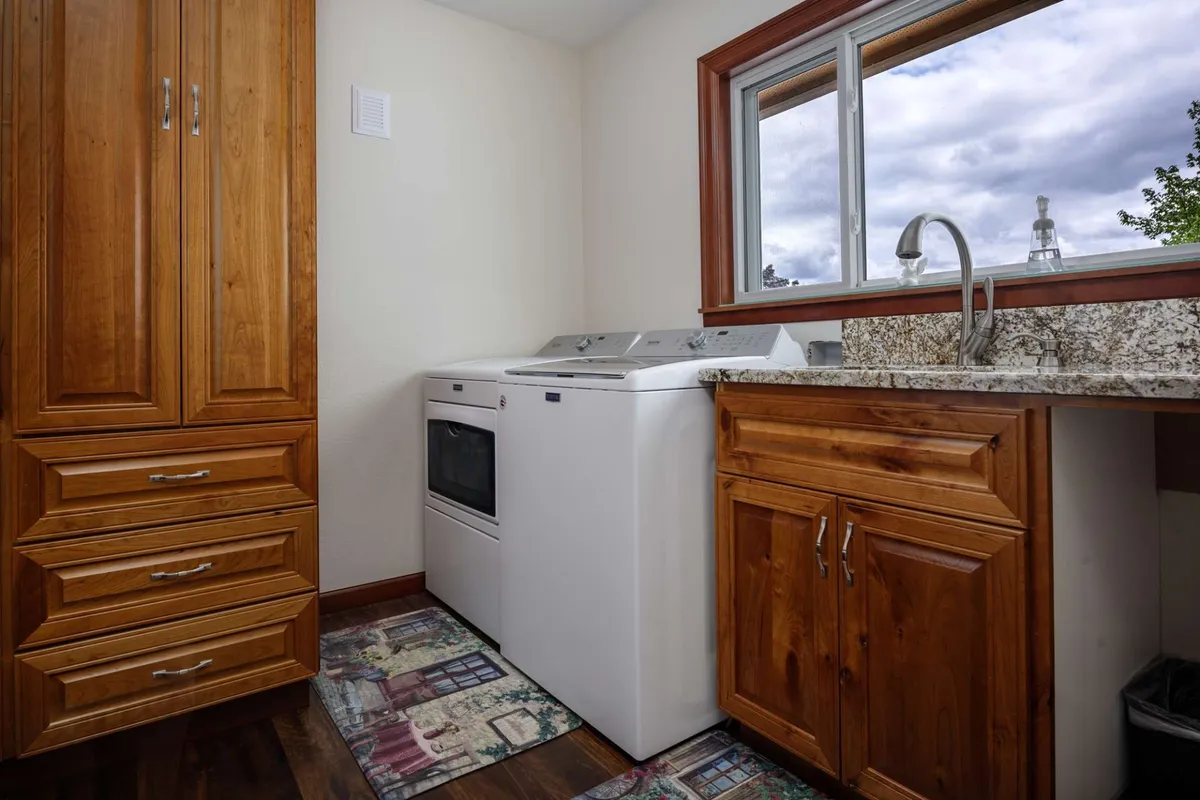 A laundry area with a washing machine beneath a granite countertop, bathed in natural light from a window that hints at an exterior view. The scene blends indoor comfort with glimpses toward the outdoors, subtly connecting home life with broader exploration.