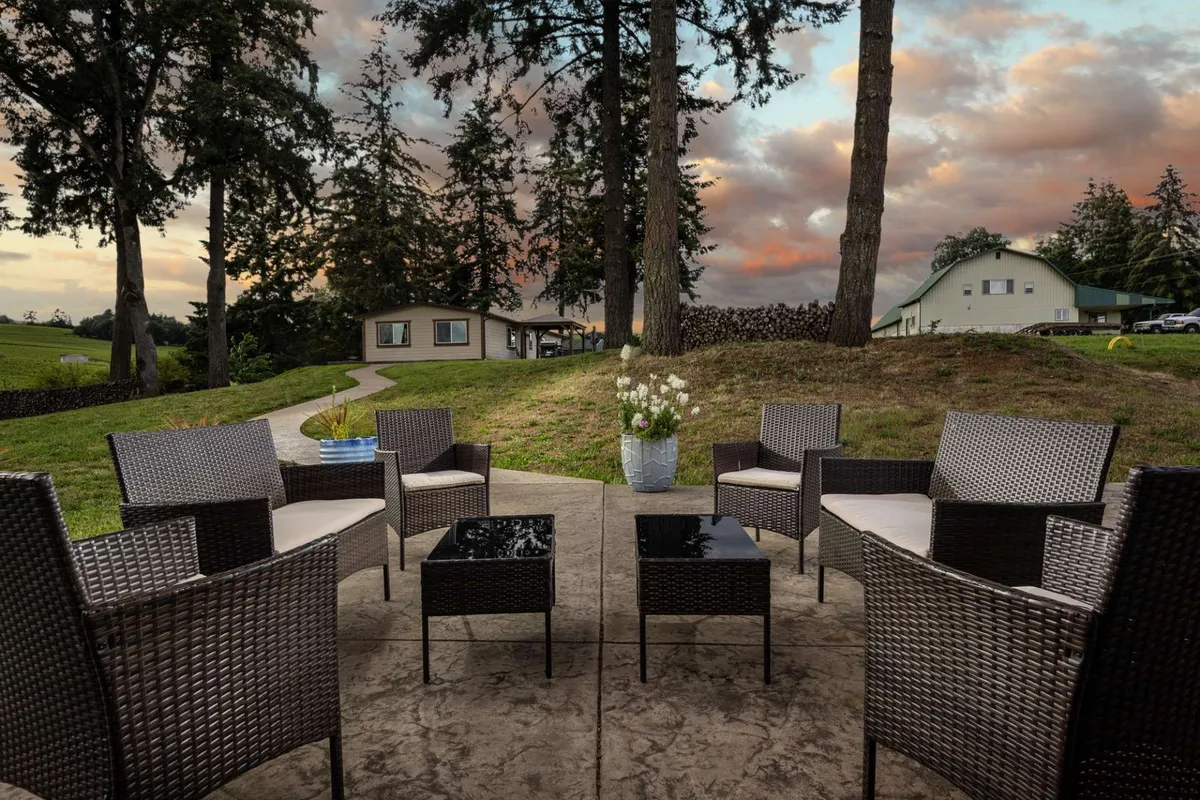 An inviting outdoor seating area with comfortable furniture, a pathway leading to the house, and vibrant flowers in a vase. The setting suggests relaxed conversations and quality time spent together as the sun sets.
